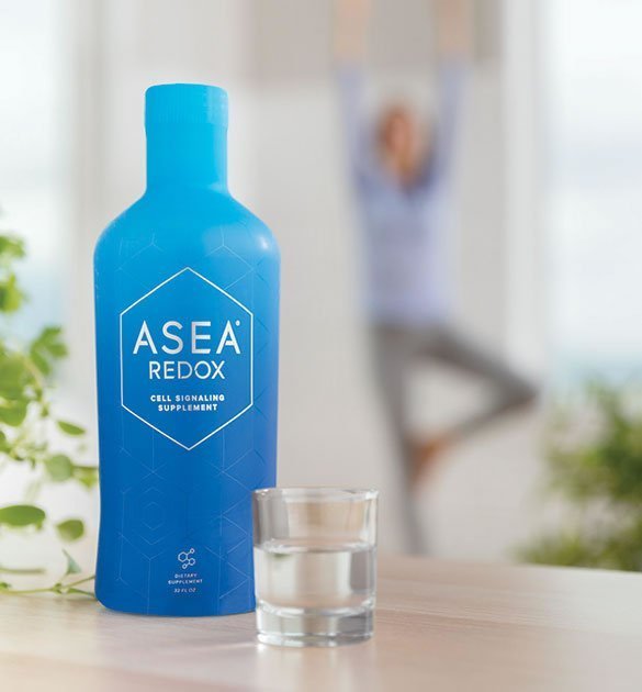 Bottle of ASEA supplement with glass on counter while woman does yoga