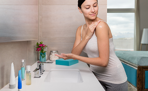 Woman applying ASEA RENU Advanced Skin Care products in the mirror